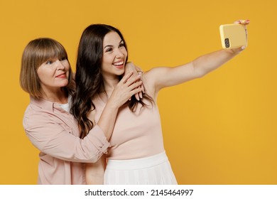 Two Side View Young Happy Smiling Daughter Mother Together Couple Women In Casual Clothes Doing Selfie Shot On Mobile Cell Phone Post Photo On Social Network Isolated On Plain Yellow Background Studio