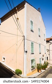 Two Sides Of Pale Apricot House With Green Shutters On Street Sorner With Pot Plants And Power Lines