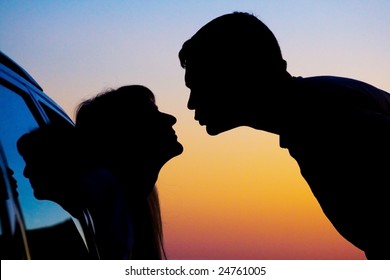 two Silhouettes of kissing people on sunset background