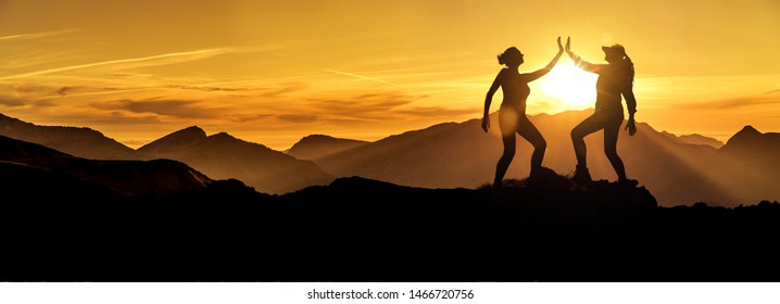 Two Silhouettes of the same woman giving herself high five on a mountain peak at sunrise, composed together in image editing - Powered by Shutterstock