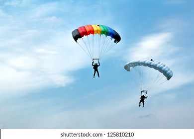 two silhouettes of unidentified skydivers on blue sky
