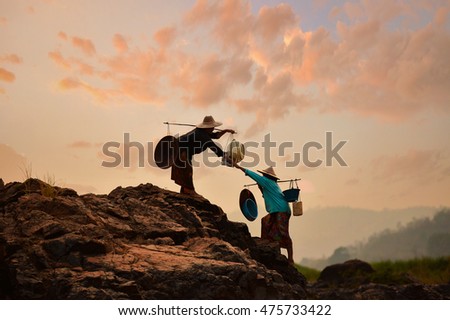 Two silluate woman fisherman to go home on during sunset,help to hand,thailand