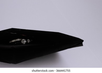 Two Silver Diamond Engagement Rings Isolated Closeup In Origami Black Boat