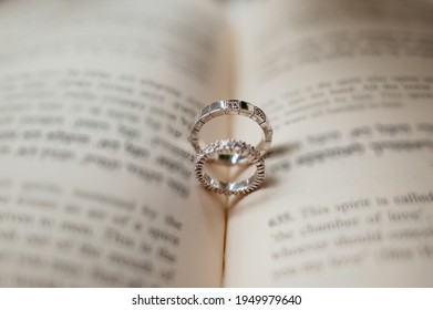 Two Silver Engagement Wedding Rings Lie On An Open Torah Book