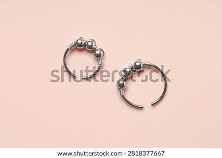 Two silver fidget rings with movable beads, stress relief and anxiety management jewelry, isolated on a pink background