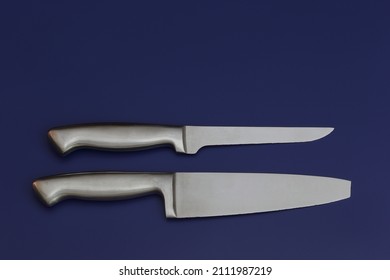 Two Silver Knives On A Blue Background. The Big Knife With A Broken Tip.