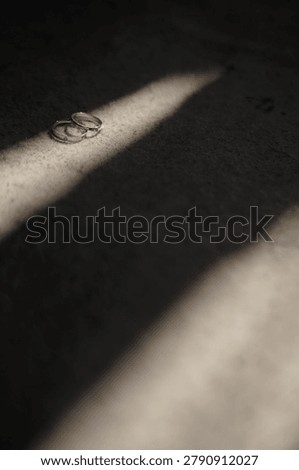 Two simple silver wedding rings in dynamic shadow ray on textured fabric background closeup