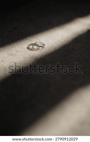 Two simple silver wedding rings in dynamic shadow ray on textured fabric background closeup
