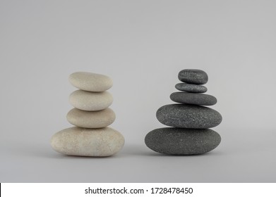 Two simplicity stones cairn isolated on white background, group of four and five black and white pebbles in tower, harmony and balance