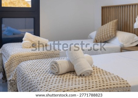 Two single beds with folded white towels and textured blankets in a modern bedroom, creating a clean and welcoming hotel or rental atmosphere