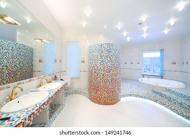Two sinks and big mirror in spacious bathroom with jacuzzi and blue and red tiles.