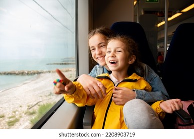 Dos hermanas miran por la ventana de un tren al mar. Las chicas están hablando y divirtiéndose. Viaje. Reflexión. Vacaciones. Verano. Vacaciones familiares.