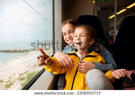 Two sister girls look out the window of a train at the sea.The girls are talking and having fun. Journey. Reflection. Vacation. Summer. Family vacation. Stockfoto © 