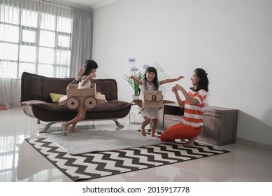 Two Sister Playing Airplane And Car Made Of Cardboard Box Running Around The House