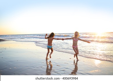 Two sisters dancing on the beach at sunset