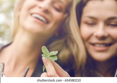 two sisters or friends hold four-leaf clover and dream of happin