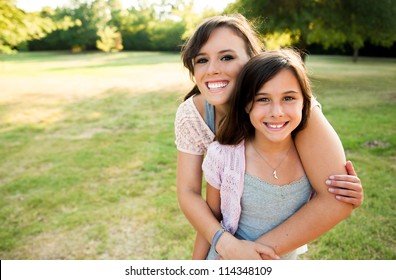 Two Sisters Hugging Outside Smiling