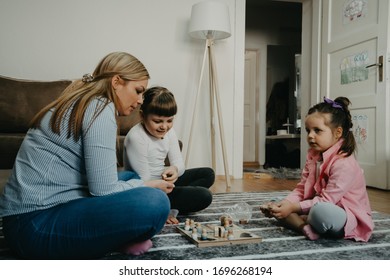 Zwei Schwestern und Mutter in medizinischer Maske spielen zu Hause bei covid-19 Quarantäne. Bleiben Sie zu Hause Aktivität für Kinder-Konzept.