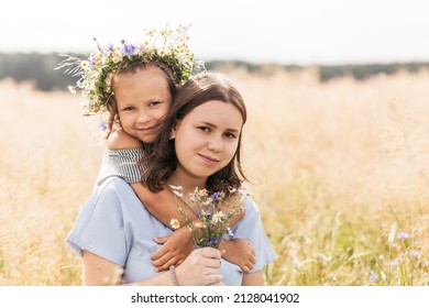 Two sisters older and younger play in the field with flowers - Shutterstock ID 2128041902