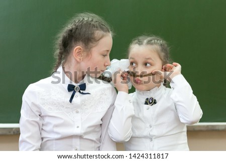 Two sisters at school are laughing at school.