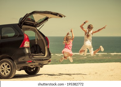 Two Sisters Standing Near A Car On The Beach