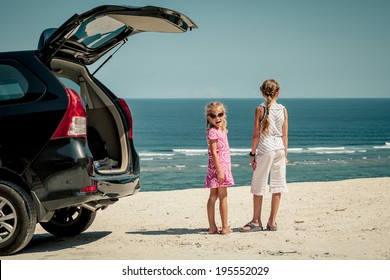 Two Sisters Standing Near A Car On The Beach