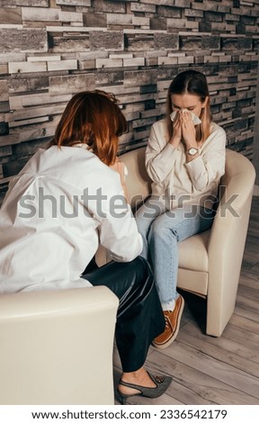 Two sisters supporting each other. Unhappy young woman crying, wiping tears with handkerchief, her friend showing compassion and trying to appease. Sad woman crying and a friend comforting her.