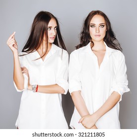 two sisters twins posing, making photo selfie, dressed same white shirt, diverse hairstyle friends