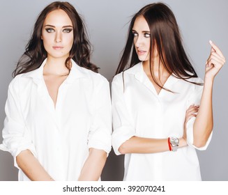 two sisters twins posing, making photo selfie, dressed same white shirt, diverse hairstyle friends