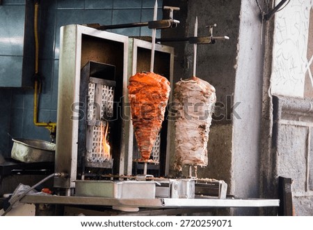Two sizzling meat spits side by side in Puebla, Mexico: fiery red al pastor and tender white arabe, a vibrant celebration of Mexican street food.