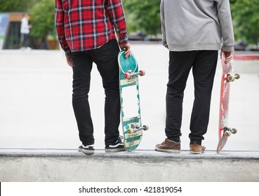 Two skater boys standing on a ramp in concrete skate park outdoors. Models holding used old skate boards ready to do tricks.  - Powered by Shutterstock