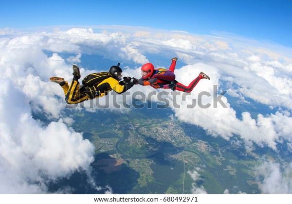 Two skydivers are flying\
in the sky.