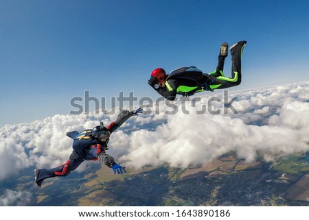 Two skydivers over the clouds during freefall