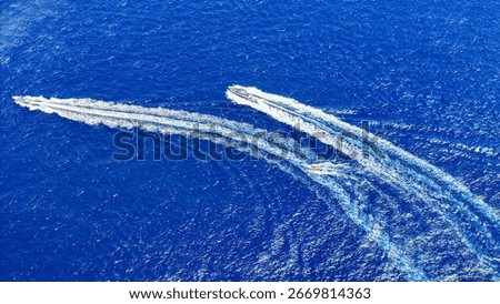 Two sleek boats skillfully navigate through the sparkling blue waters, creating trails of frothy white foam under the brilliant sun. The excitement of the race fills the air as they speed ahead.