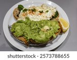 Two slice of sourdough bread toastwith avocado paste with black pepper and egg white crab meat on another slice. Lemon slice on the side on a white plate 