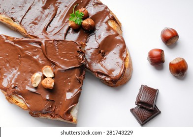 Two Slices Of Bread With Chocolate Cream And Hazelnuts White Isolated Top View. Hazelnut And Chocolate Decoration.