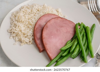  Dos rebanadas de jamón servidas con mantequilla de arroz y judías verdes