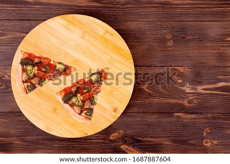 Two slices of pizza with veggie vegetables, on bamboo bottom, on wooden table, top view space for text