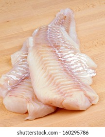 Two Slices of Raw Fresh Cod Fish Fillet closeup on Wooden Cutting Board