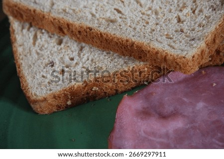 Two slices of wheat bread and some ham or deli lunchmeat and grapes on a plate for lunch snacktime dinner or breakfast