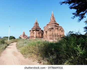 Two Small And Almost Identical Brick Pagodas Stand Next To Each Other On A Meadow In Bagan, Burma.