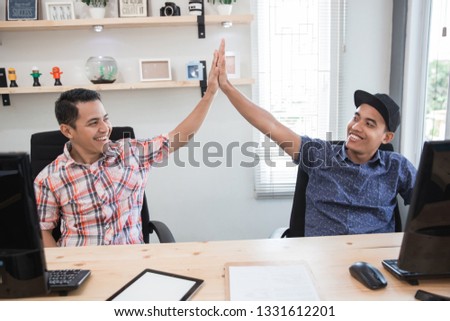 two small business partner highfive success in the office
