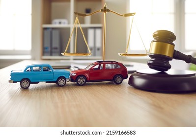 Two Small Cars On Table In Courtroom. Gavel And Little Toy Car Models On Desk In Courthouse. Road Crash, Law, Justice, Lawyer Services, Civil Trial, Accident Case Study, Insurance Coverage Concept