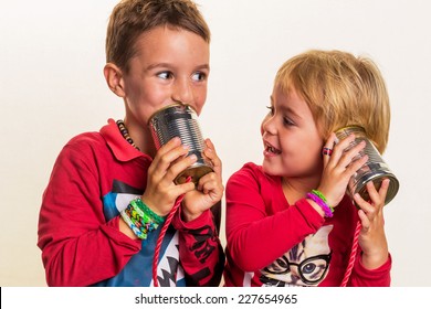 Two Small Children Are Talking To An Telephone Of Two Doses.