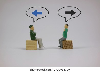Two small figures face each other on a wooden block, sharing ideas that imply dialogue, choices, and different directions. Isolated on an white background.