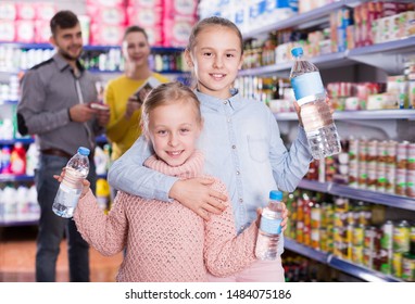 Two Small Nice Sisters Holding Bottled Water During Family Shopping In Supermarket