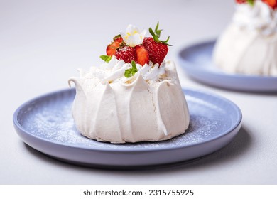 Two small pavlova cakes from meringue decorated with fresh strawberries on a pink plate. Bright scene with flowers as decoration. - Powered by Shutterstock