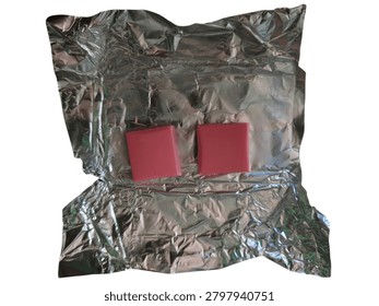 Two small red square pieces placed on a crumpled sheet of reflective silver metallic foil, creating a high contrast modern abstract composition.
