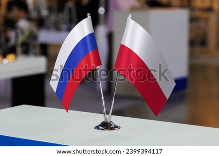 Two small table flags of Russia and Poland together at some event or fair, as a symbol of cooperation between the two states. Joint business of Poland and the Russian Federation