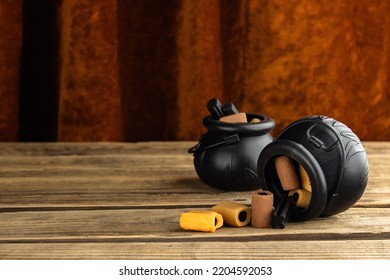 Two Small Toy Witches' Cauldrons With Different Candies Stand On A Wooden Table, With A Vintage Velvet Curtain In The Background.  One Pot Fell Out Of It, Sweets Slept. Halloween